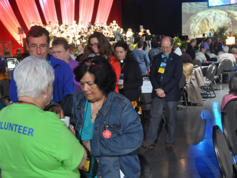 a group of people approach a volunteer for communion elements